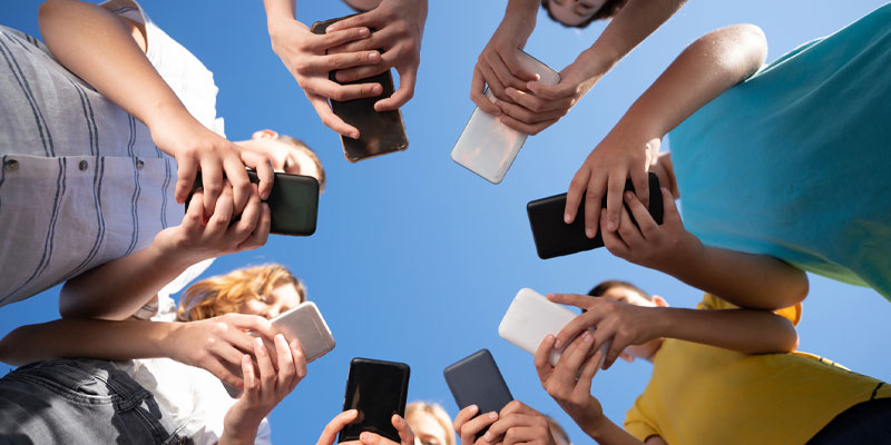 Teens standing in circle on mobile phones