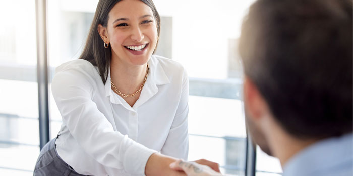young business woman shaking man's hand in office