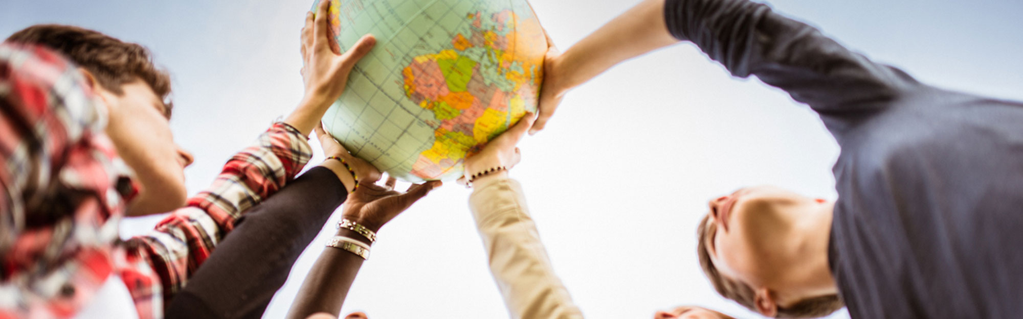 adult students of different ethnicities holding up a globe